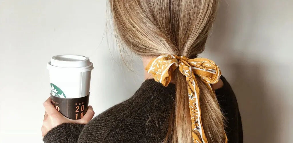 A woman with long blonde hair holding a cup of coffee.