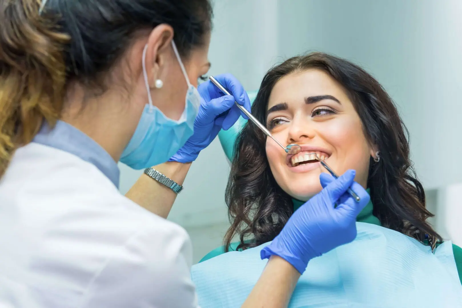 A woman getting her teeth checked by an dentist.