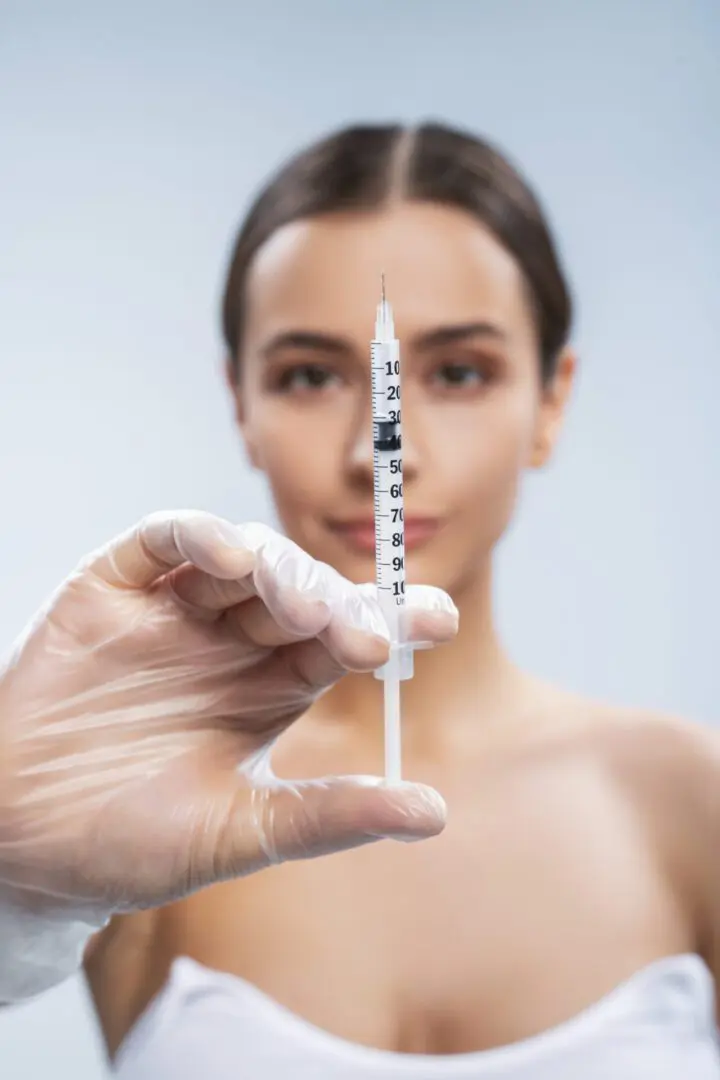 A woman posing for a picture with an injection in her hand .