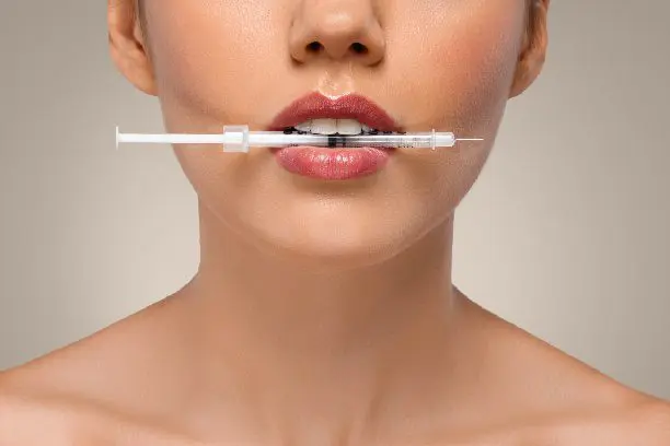 A woman posing with an injection in her mouth.