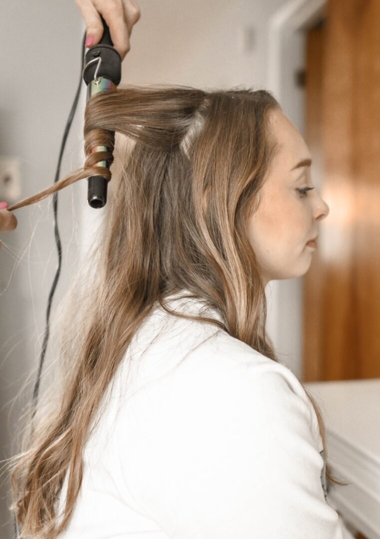 A woman blow drying her hair with a green brush.